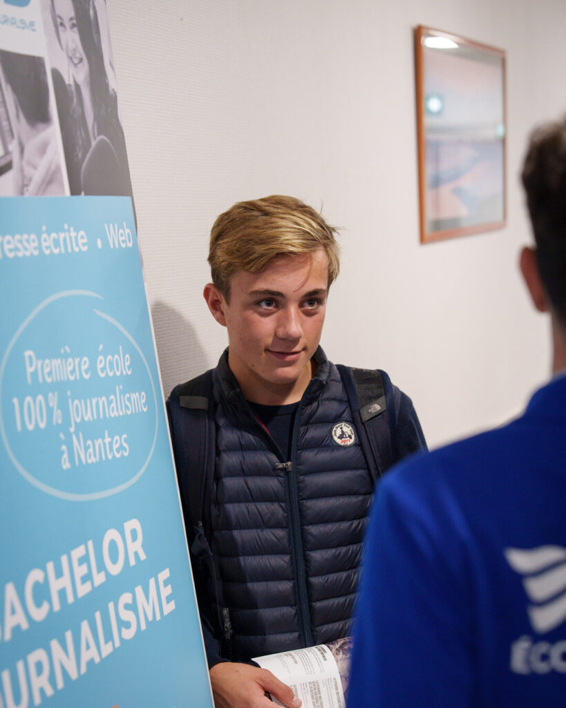 Un lycéen, brochure en main, devant le kakémono « Bachelor journalisme, première école 100 % journalisme à Nantes » du Centre Nantais de Journalisme.